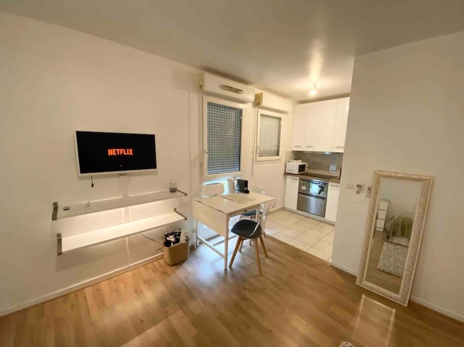un salon avec une table et une télévision sur un mur dans l'établissement Studio CosyLux proche Paris Stade De France, à Saint-Denis
