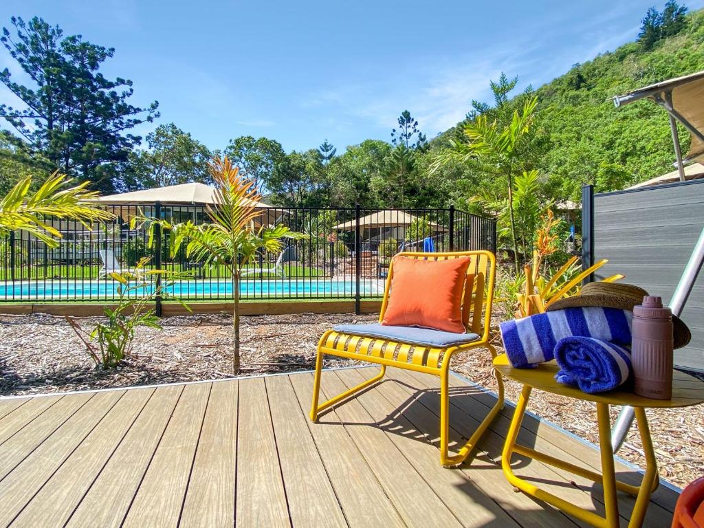 einen Stuhl und einen Tisch auf einer Terrasse mit einem Pool in der Unterkunft Magnetic Glamping Tent 10 in Nelly Bay