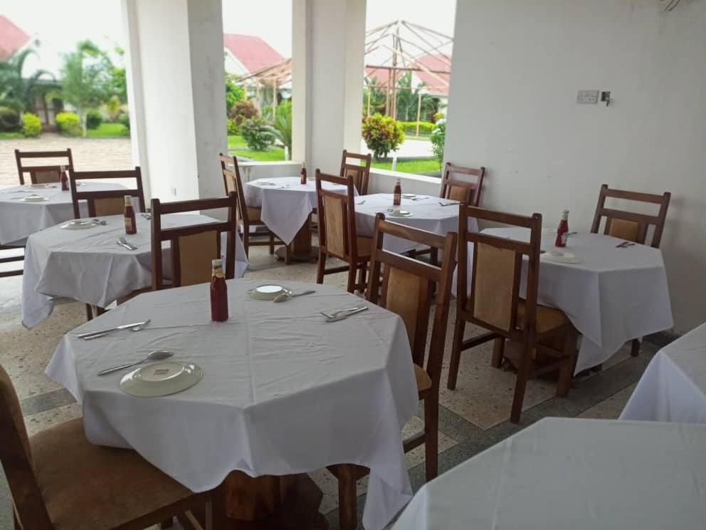 um restaurante com mesas e cadeiras com toalhas de mesa brancas em Taj hotel partnership em Nungwi