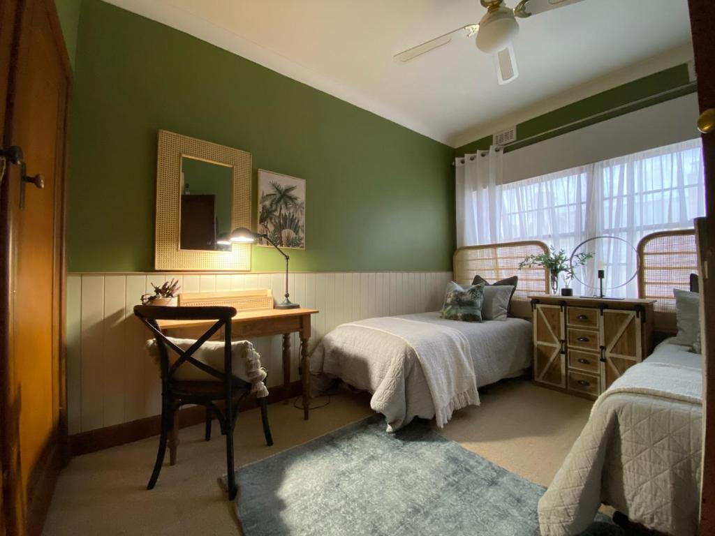 1 dormitorio con 2 camas, escritorio y espejo en The Miner's Rest, en Stawell