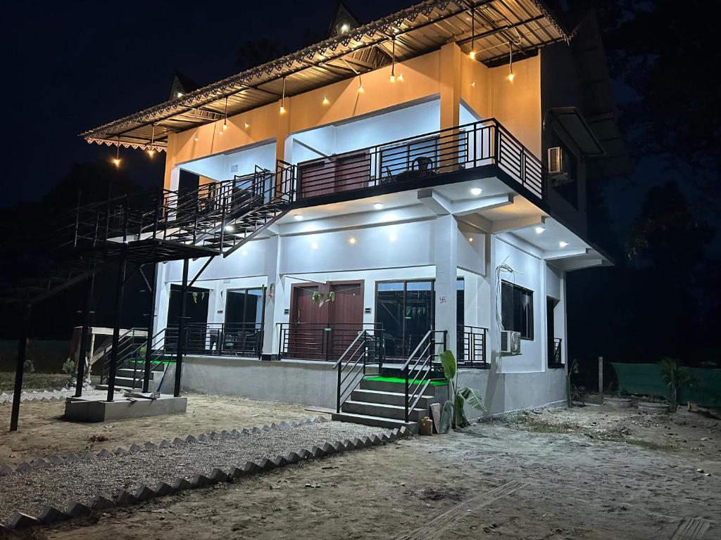 a building with a balcony and stairs in the night at AAHI'S CHILAPATA JUNGLE STAY in Fālākāta