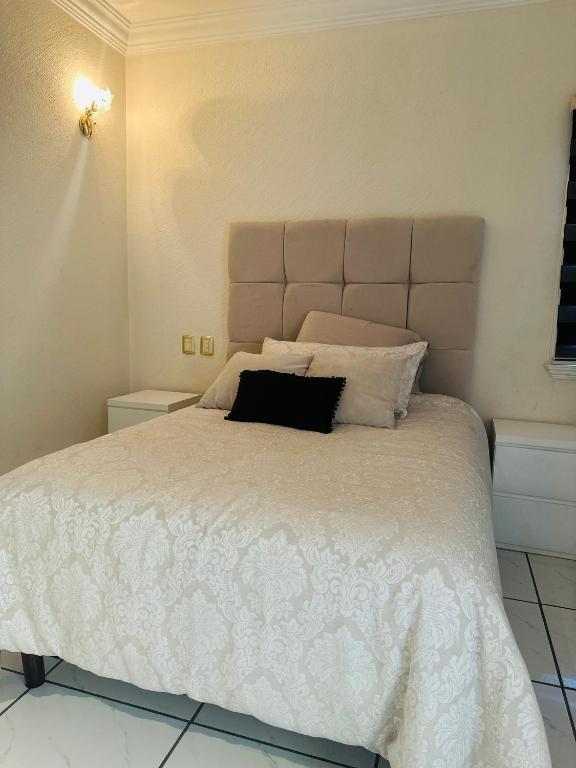 - une chambre avec un grand lit blanc et un oreiller noir dans l'établissement Habitación en casa dentro de residencial céntrico, à Toluca