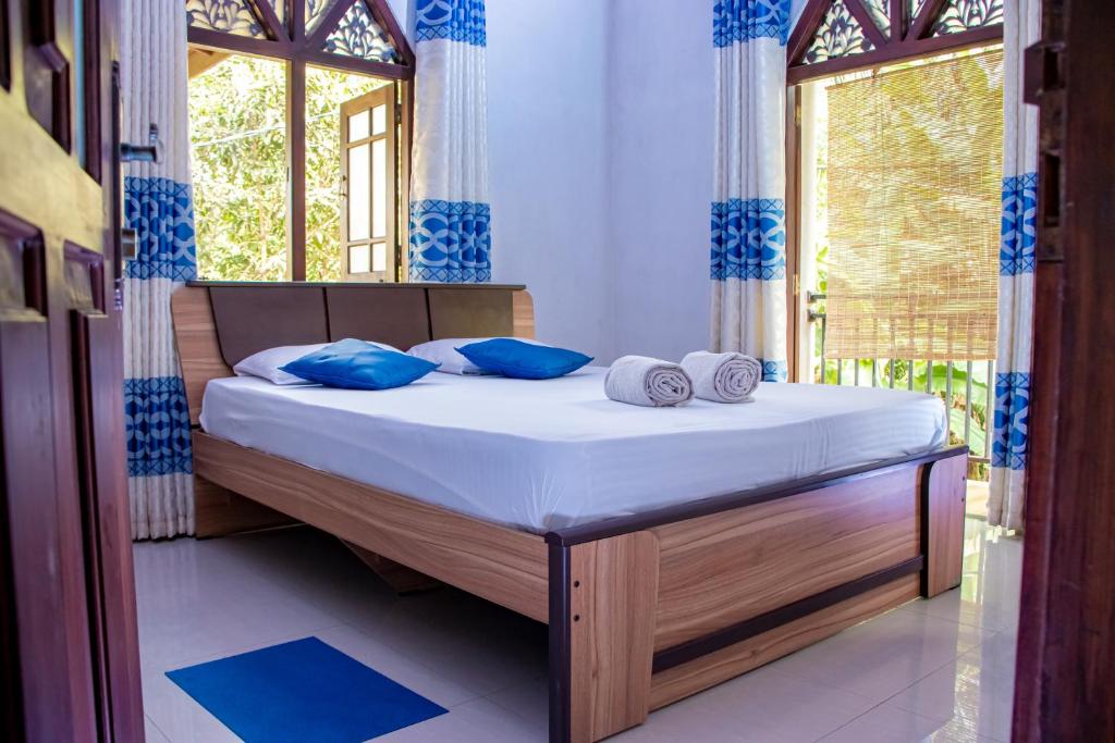 a bedroom with a bed with blue pillows and a window at DiNi Galle in Galle