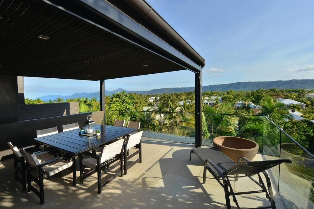 d'une terrasse avec une table et des chaises sur un balcon. dans l'établissement Hapuka - Luxury Villa with Stunning Views on Murphy St, à Port Douglas