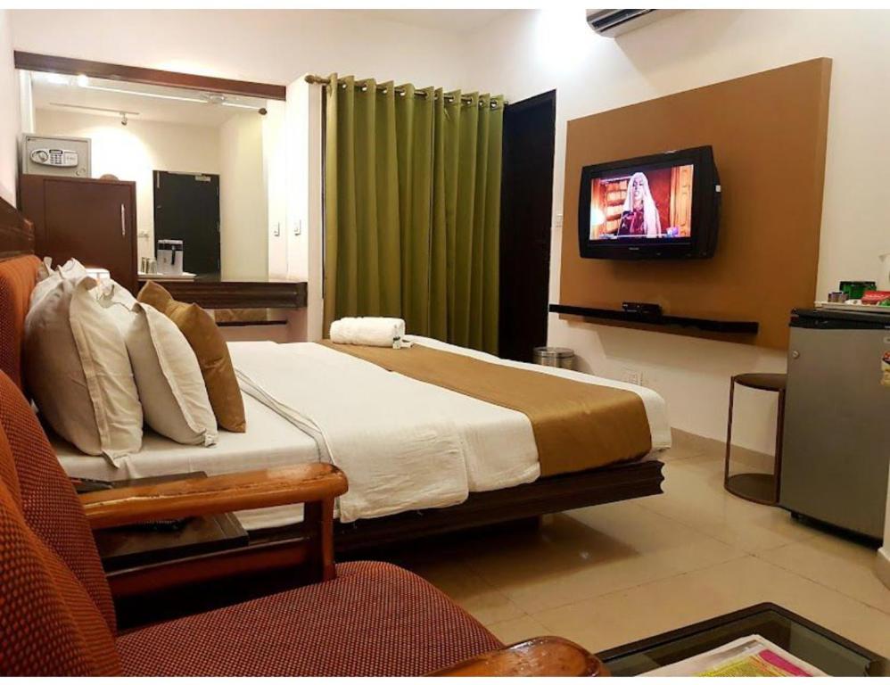 a hotel room with a bed and a tv at Hotel White Tree, Chandigarh in Chandīgarh