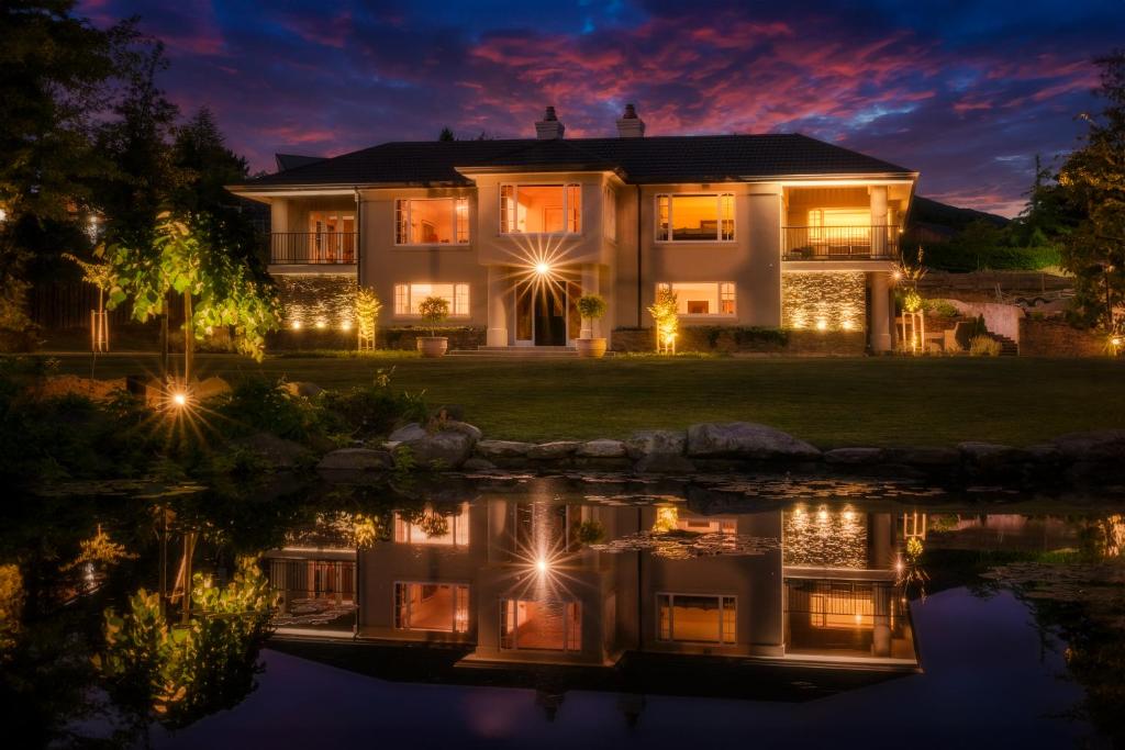 een huis verlicht in de nacht met lichten in het water bij Oakview in Hanmer Springs