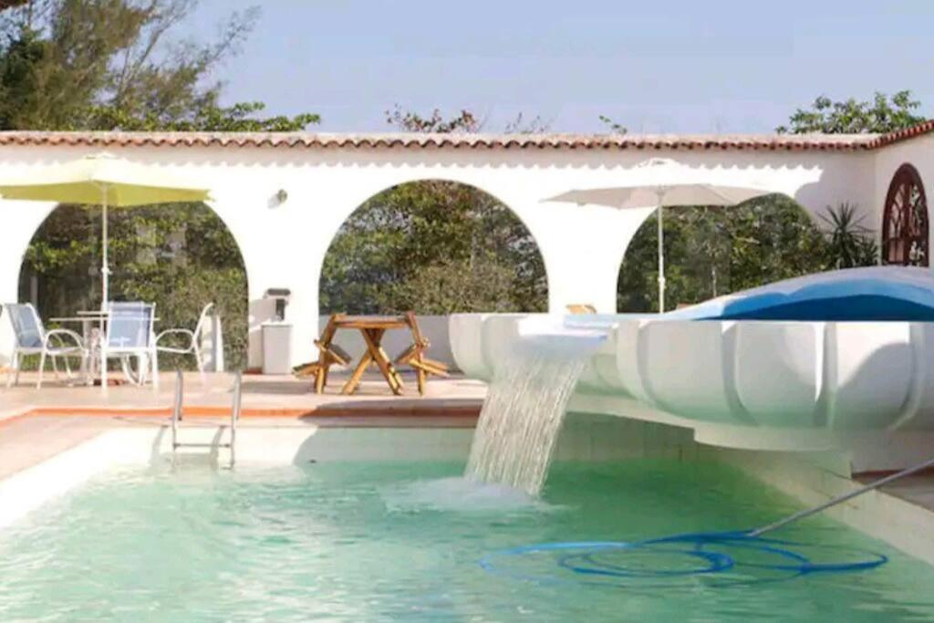 una piscina con fontana di A Famosa CASA BRANCA da Barra! Suíte 6 c/ HIDRO a Rio de Janeiro