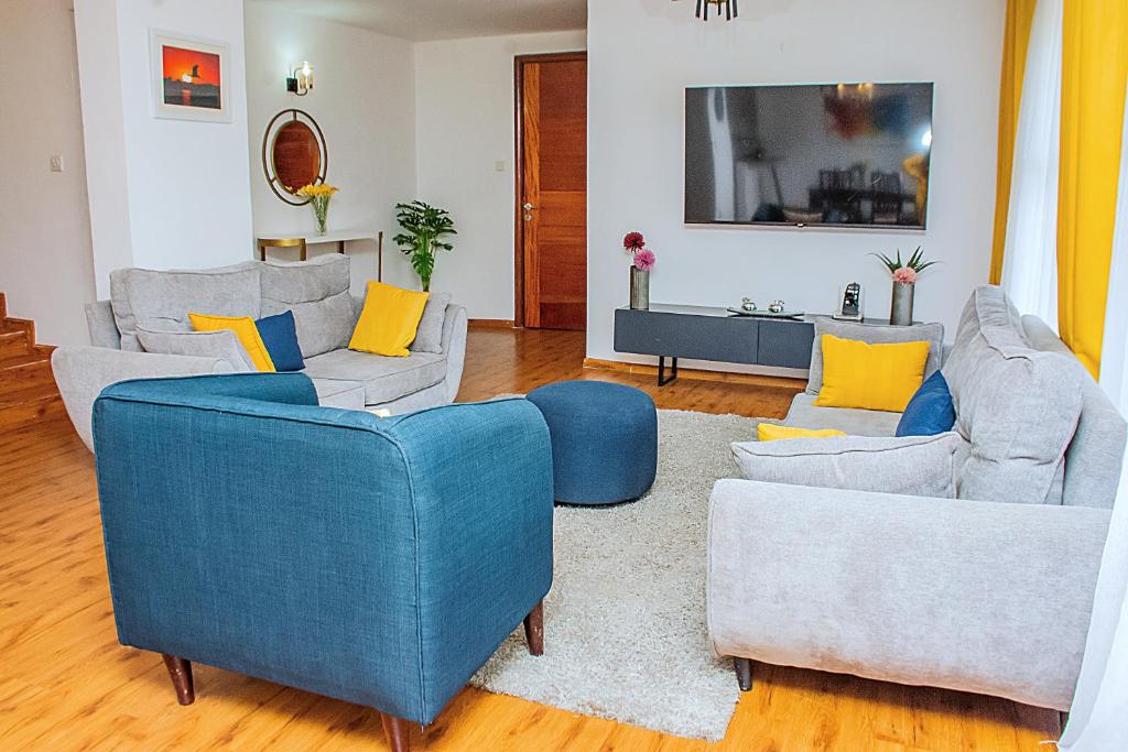 a living room with two blue chairs and a couch at Casa Misa Riverside Duplex in Nairobi