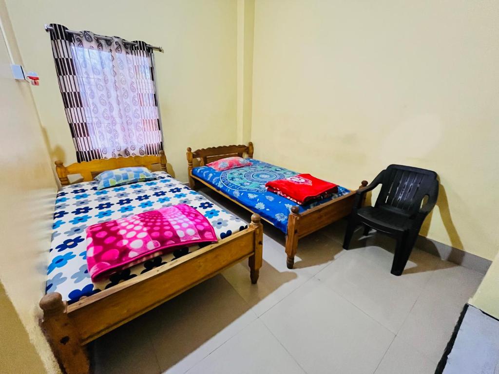 2 camas y una silla en una habitación en MANAS LODGE/HOTEL (NOOR MARKET), en Bongaigaon