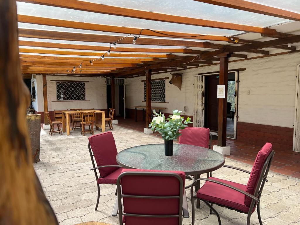 un patio con mesa, sillas y pérgola de madera en Steingarten, Casa de Campo hermosa y amoblada., en Riobamba