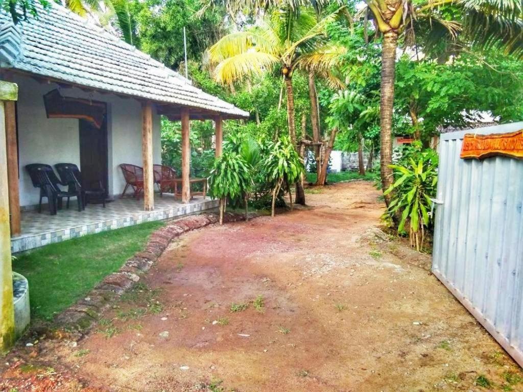 a backyard of a house with a fence and palm trees at Beach Island Villas in Kollam