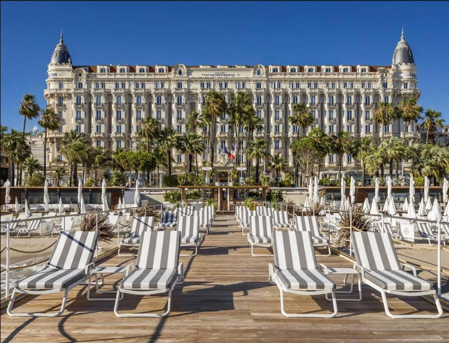 une rangée de chaises longues devant un bâtiment dans l'établissement Le Canada - 2Pièces Croisette plage derrière le Carlton calme, à Cannes