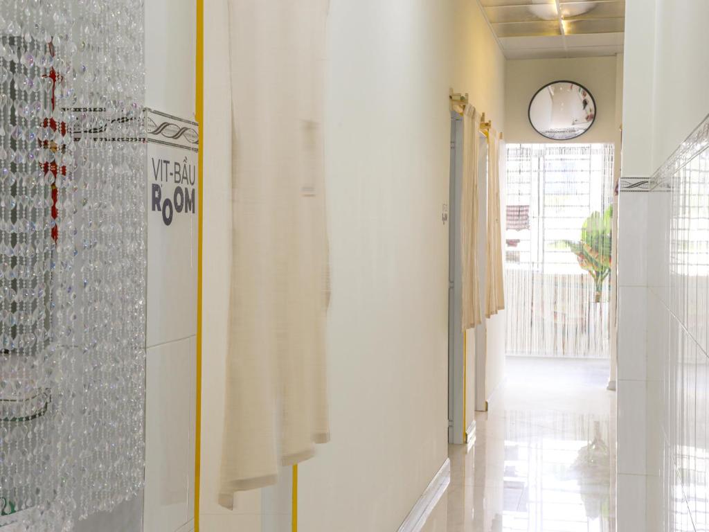 um corredor com paredes brancas e um relógio na parede em Vit-bau Room - Double Room 2 person - Duck Homestay Ben Tre em Ấp Phú Lợi