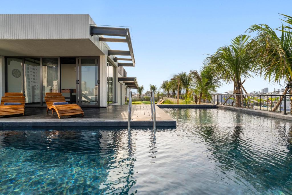 A sunlit pool beside a modern villa-style building.