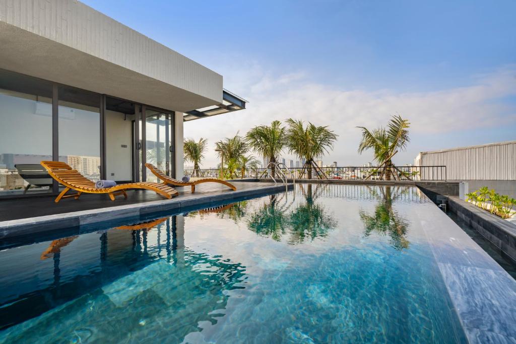 A rooftop pool beside a glass-walled room and a row of wooden loungers.