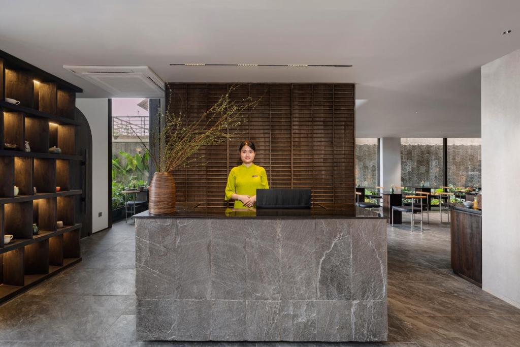 A reception counter sits in an open, modern lobby with a laptop and illuminated shelving.