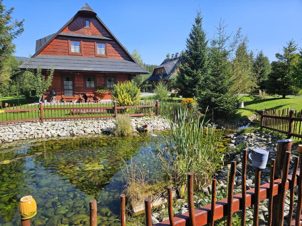 a home with a pond in front of a house at Drevenice Zuberec in Zuberec