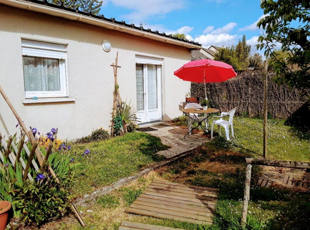 d'une terrasse avec une table et un parasol rouge. dans l'établissement Grand studio sur jardin Nantes Beaujoire B, à Nantes