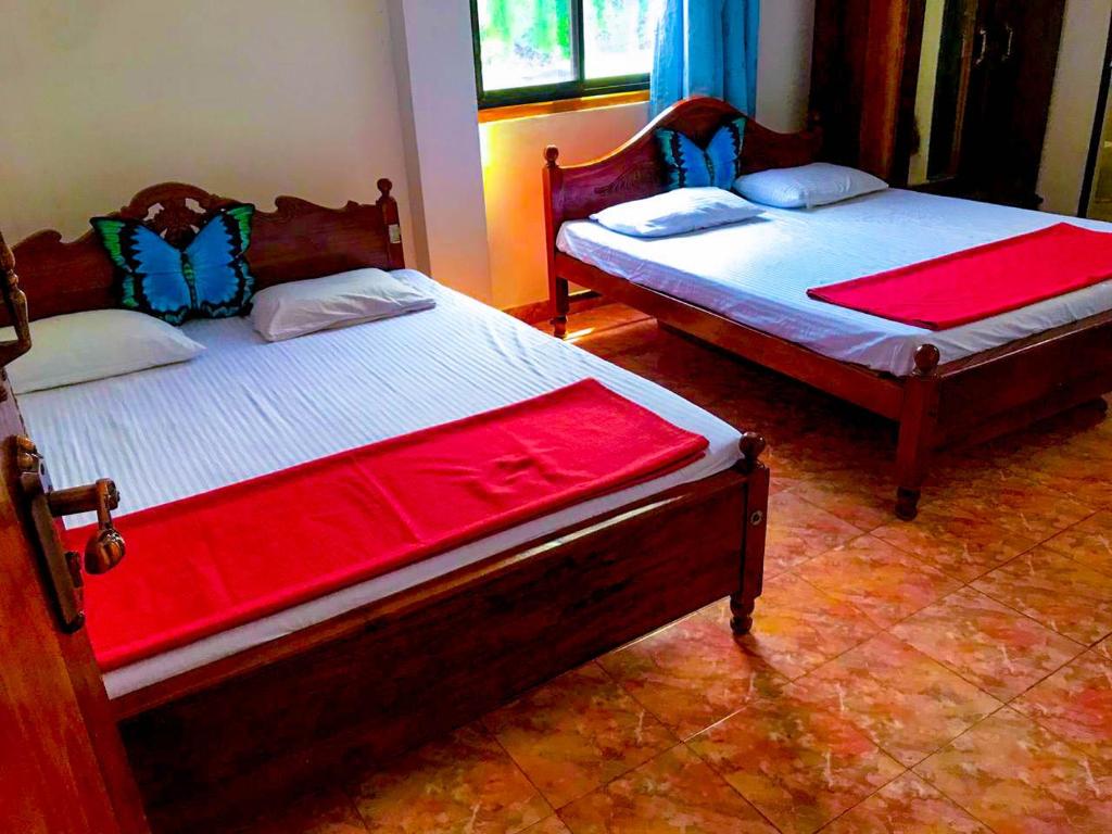 two beds sitting in a room with red sheets at Geesh Residence : Rooms in Jaffna in Jaffna