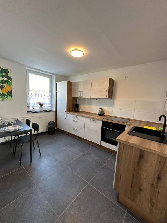 eine Küche mit weißen Schränken, einem Tisch und einem Fenster in der Unterkunft Schöne Apartments am Wasserturm Rheydt in Mönchengladbach