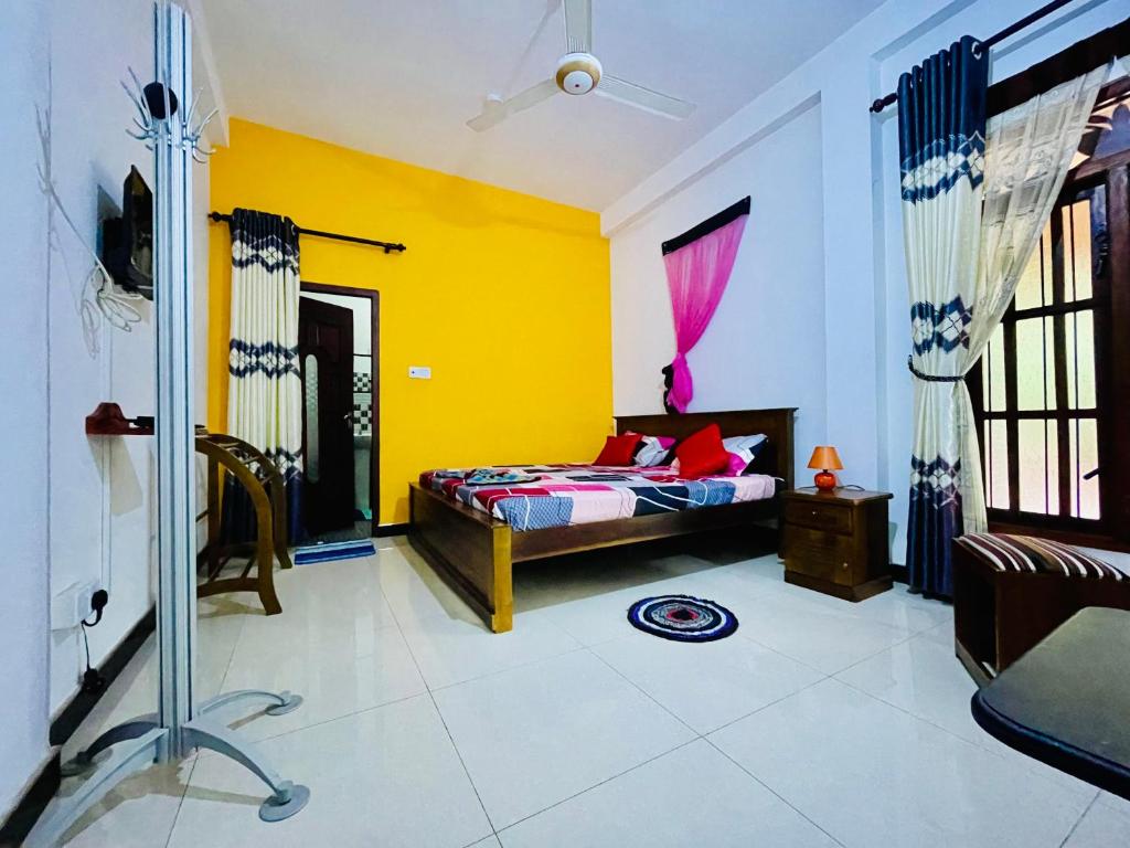 1 dormitorio con cama y pared amarilla en Rathnayake Rest, en Badulla