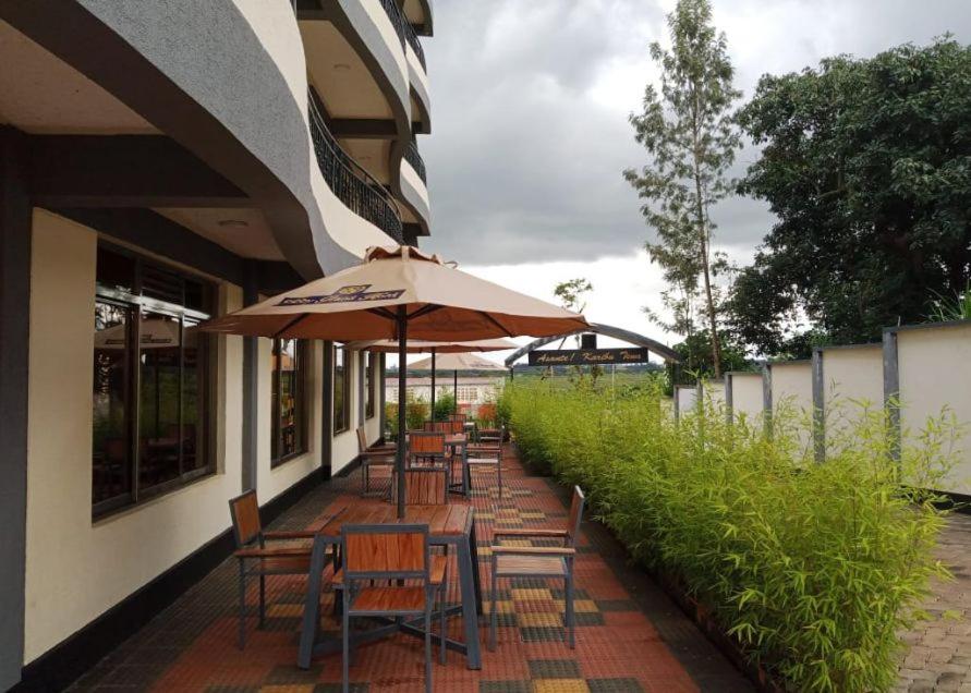 a patio with tables and chairs and an umbrella at Sabby Grand Hotel in Ithumba