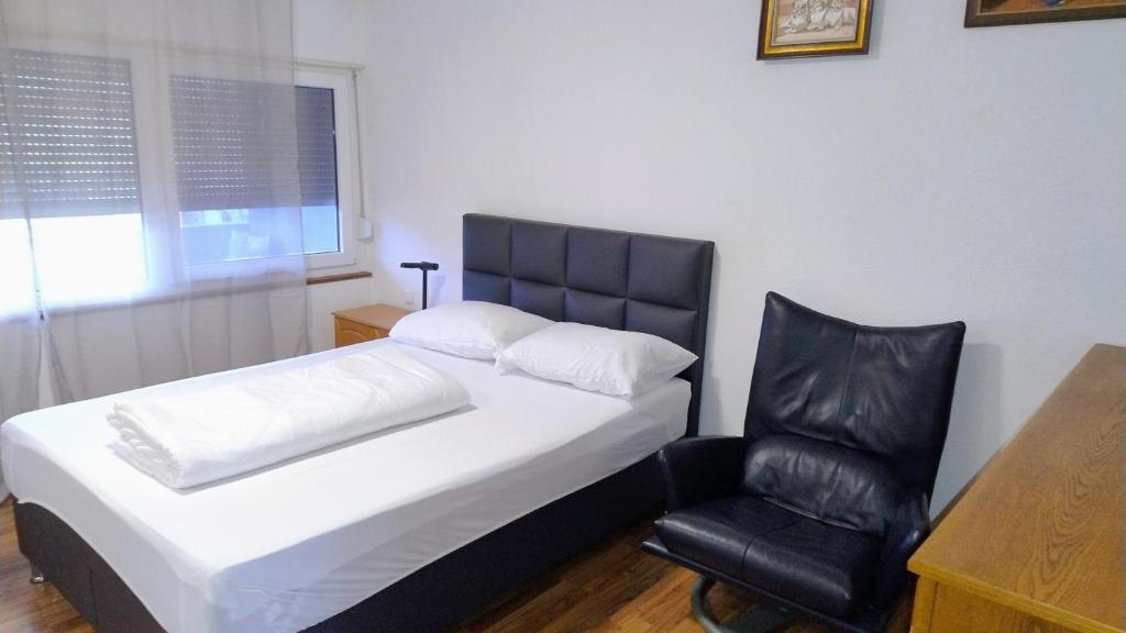 1 dormitorio con 1 cama y 1 silla negra en Room in shared apartment, en Friedrichshafen