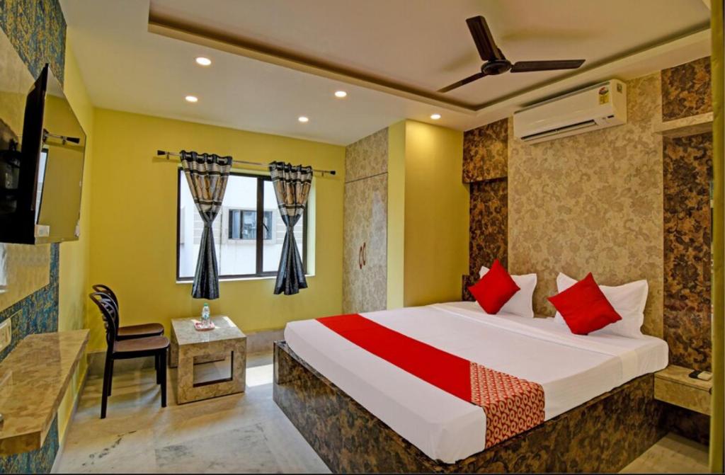 a bedroom with a bed with red pillows and a table at Hotel Divine Chariot in kolkata