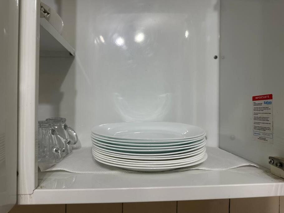 a stack of plates sitting on a shelf in a microwave at Casa próxima ao Centro in Caraguatatuba
