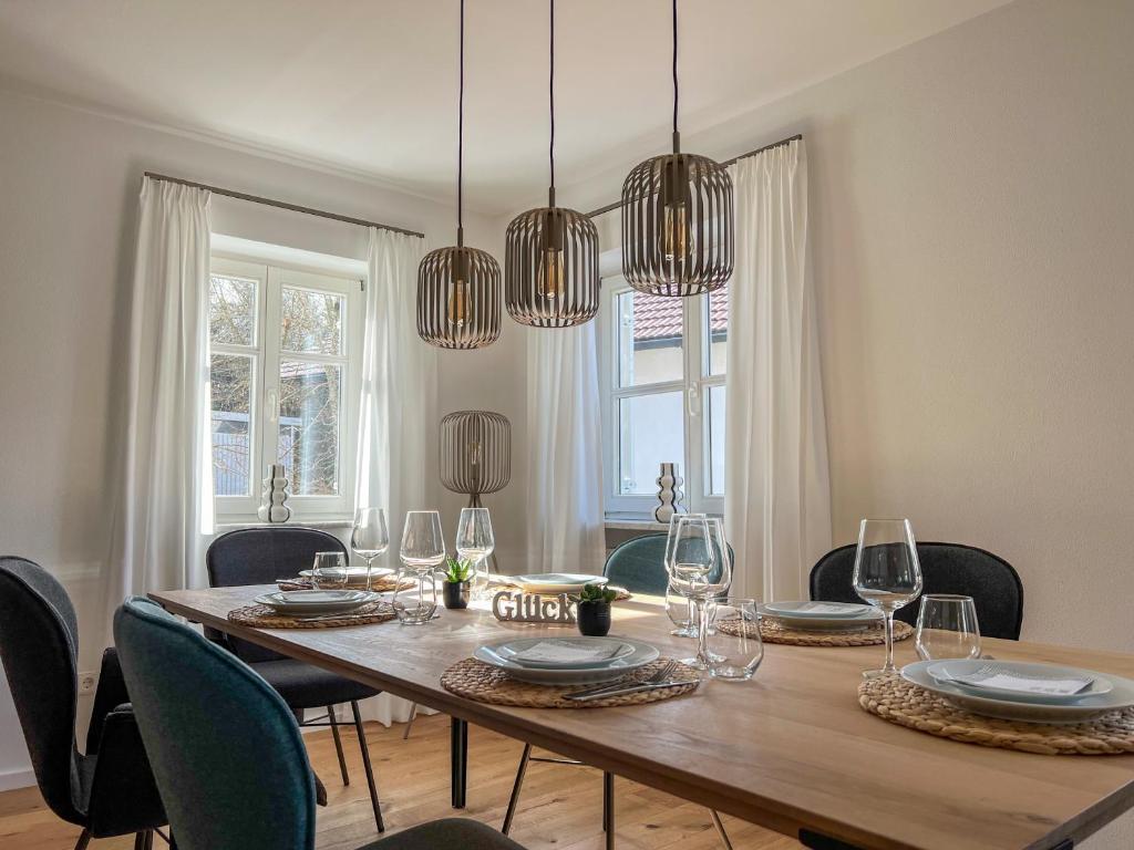 una sala da pranzo con tavolo, sedie e lampadari a braccio di Ferienhaus Goldstück im Allgäu a Kaufbeuren