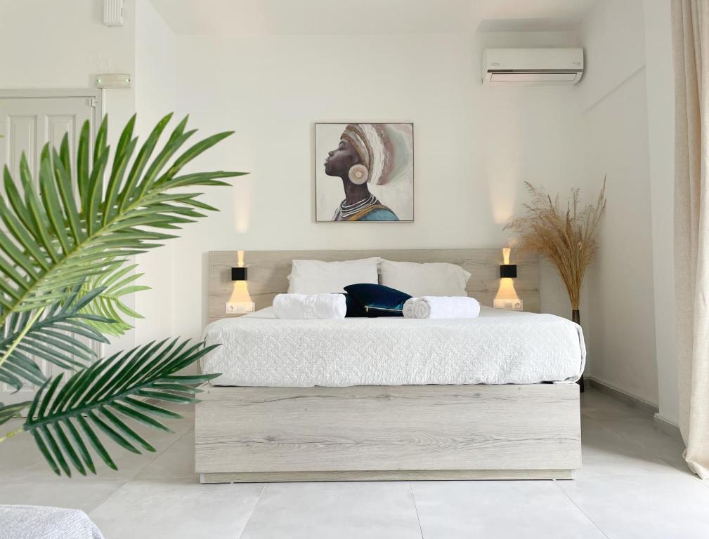 レティムノ・タウンにあるSunset Seaside Apartments & Studiosの白いベッドと植物が備わるベッドルーム1室