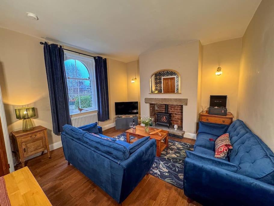 sala de estar con 2 sofás azules y chimenea en Beautiful, Relaxing Home in Central Saltaire en Saltaire