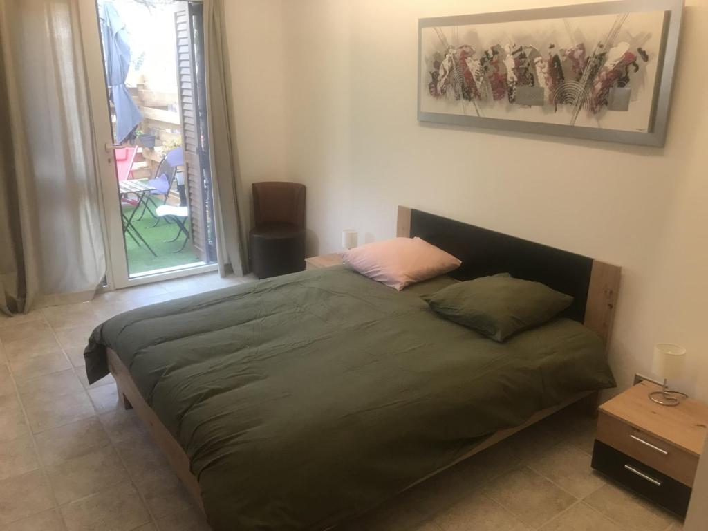 1 dormitorio con cama verde y ventana en A Casa Assulanatta en Santa-Reparata-di-Balagna