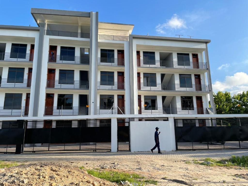 a man walking in front of a building at Stylish 1-Bedroom Apartments with Amazing Views in Dar es Salaam
