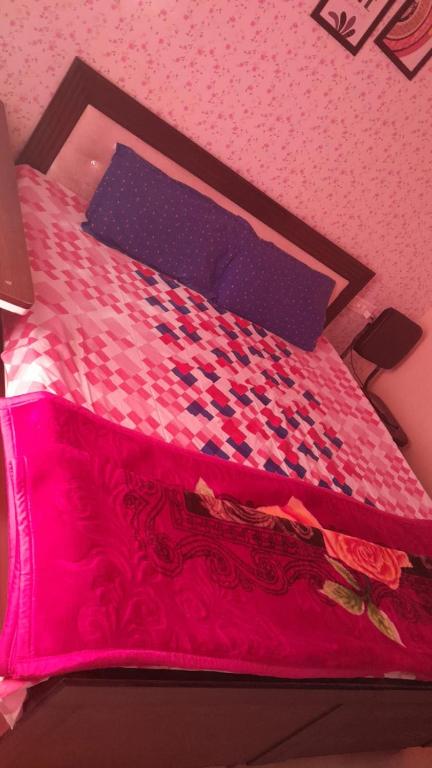 a bedroom with a bed with a pink comforter at Rellio Bed and Breakfast in Kharar
