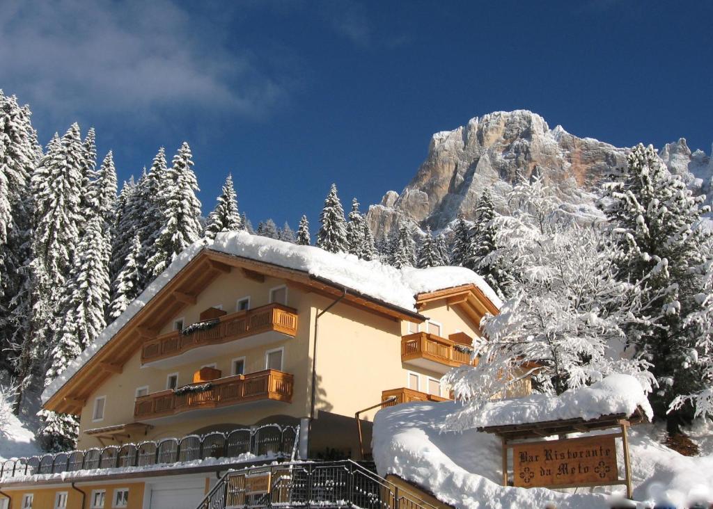 a building covered in snow in front of a mountain at Appartamento da Meto in San Martino di Castrozza