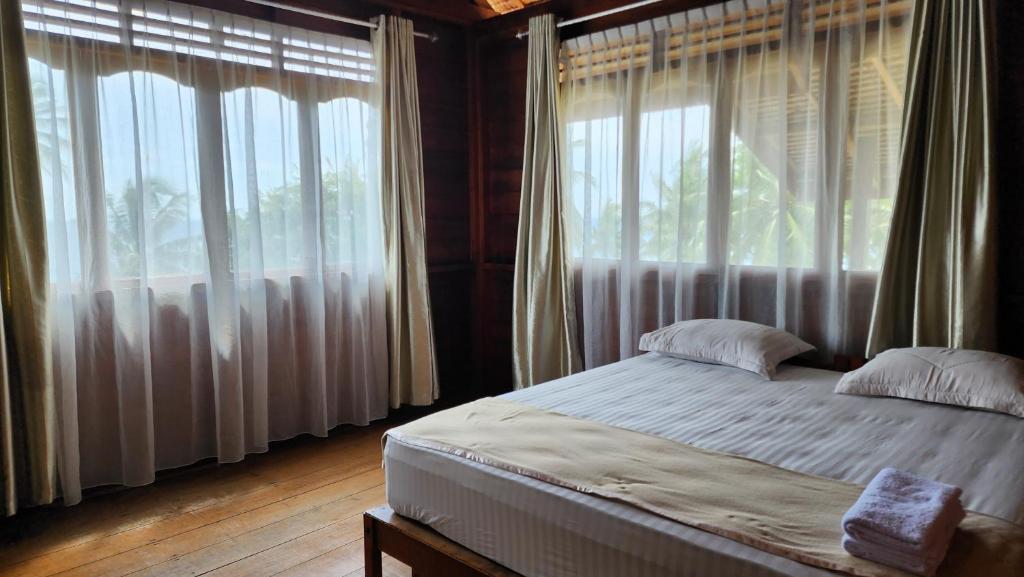 a bedroom with a bed and large windows at UKCC (Ujung Karang Conference Center) in Sabong