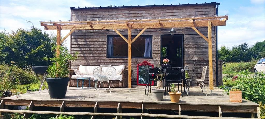 eine Hütte mit einem Tisch und Stühlen auf einer Holzterrasse in der Unterkunft Tiny house bucolique in Saint-Brieuc-de-Mauron