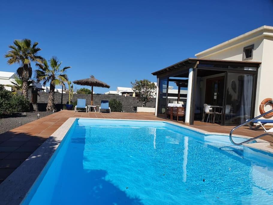 a blue swimming pool in front of a house at Villa La Carabela 35 in Playa Blanca