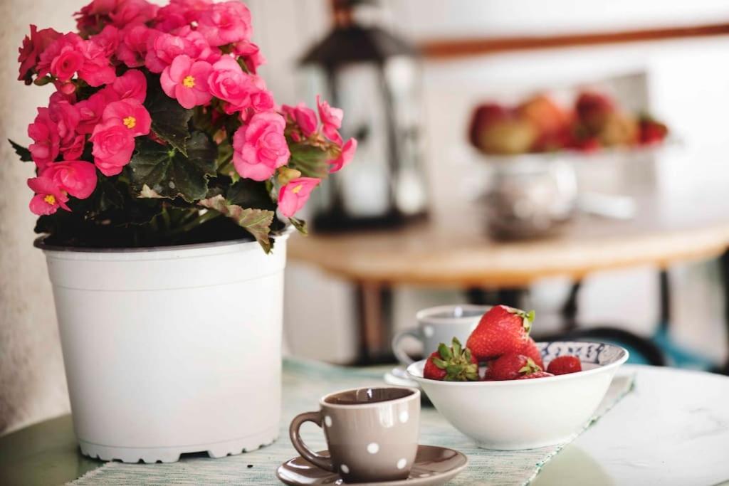 a table with a vase with flowers and a bowl of strawberries at Lovely,central, spacious 2-bedrooms apartment in Piraeus