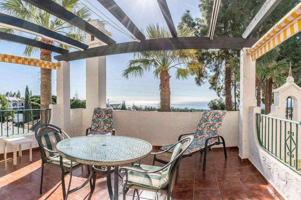 a patio with a table and chairs and palm trees at Golf/Seaview 2 bedroom apartment in Sitio de Calahonda - Mijas in Mijas