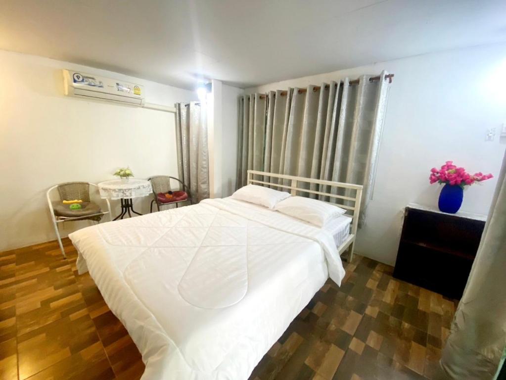 a bedroom with a white bed and a table at Sleep Home Khaoyai in Pak Chong