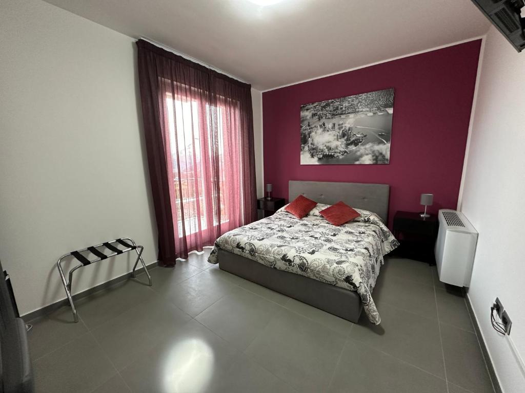 - une chambre avec un lit et un mur violet dans l'établissement Lotelito Apartment, à Fisciano