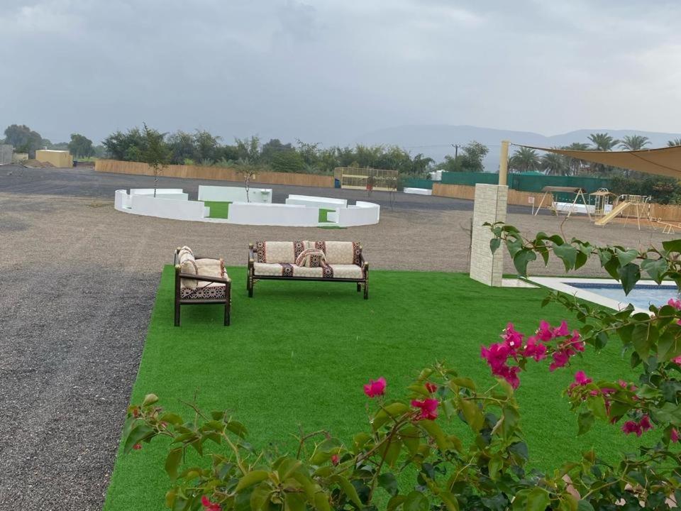 een tuin met twee banken en bloemen en een zwembad bij استراحه الليوان ALliwan Rak 1 in Ras al Khaimah