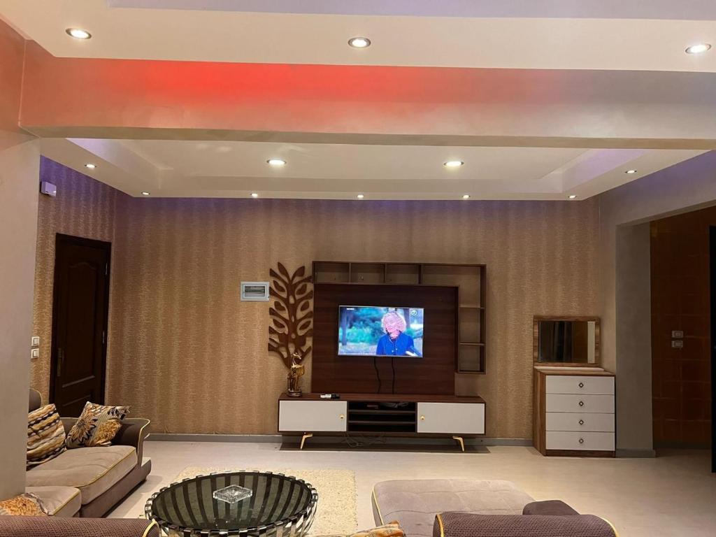 a living room with a flat screen tv on a wall at Cozy Apartmen with Garden in Sheikh Zayed in Sheikh Zayed