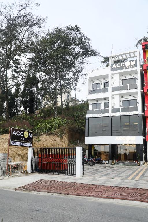 a large white building with a sign in front of it at Accom Hotel in Ilām