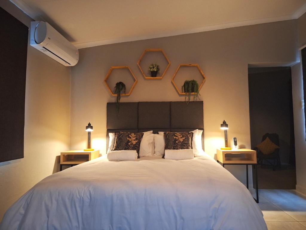 1 dormitorio con 1 cama blanca y 3 cuadros en la pared en Wisteria Cottages, en Bloemfontein