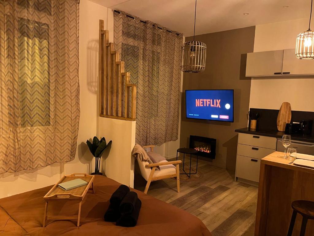 a living room with a couch and a tv at SUITE Serenity Room SPA- Balnéothérapie in Saint-Étienne