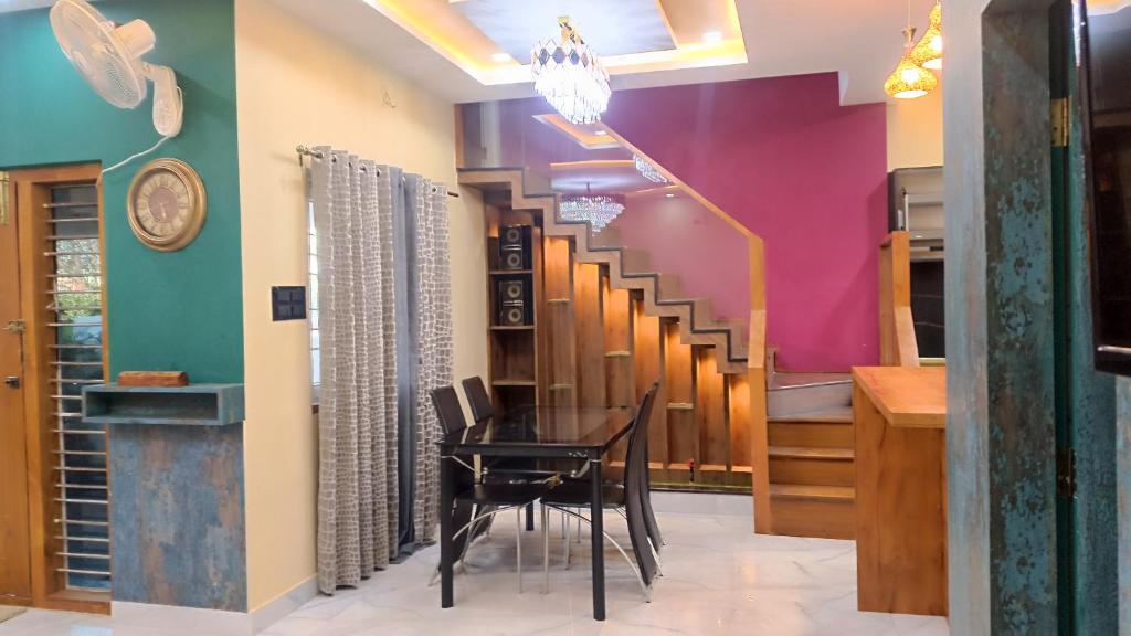 a dining room with a table and a staircase at Lavish inn homestay in Mysore