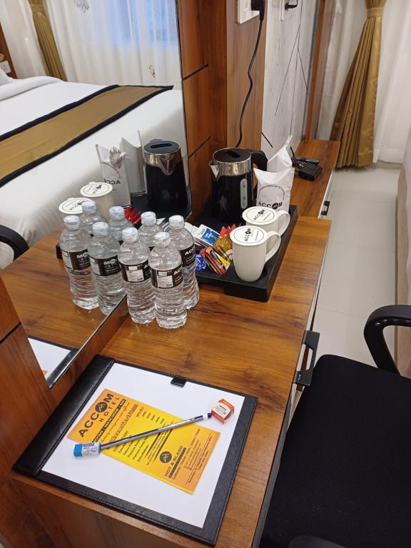 a table with bottles of water and a tablet on it at Accom Hotel in Ilām